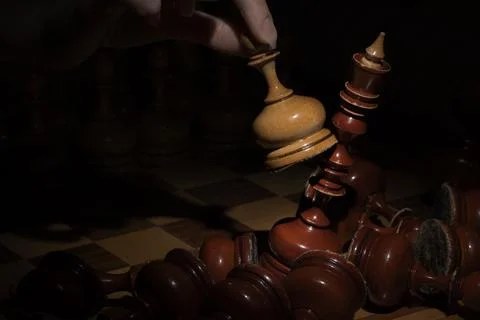 Female hand playing chess and beat the king on a dark background. old chess Stock Photos