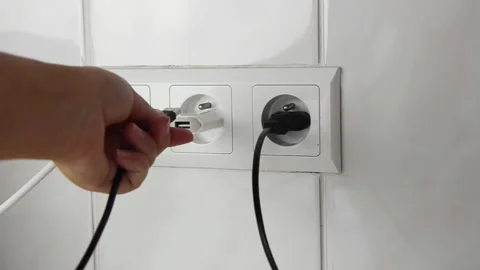 Female hand plugging an electrical power plug into a wall socket. 스톡 동영상 339006820