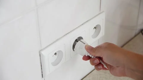 Female hand plugging an electrical power plug into a wall socket. 스톡 동영상 339006896