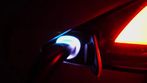 Female hand plugging out a charger from electric car at night time. Arm of young Stock Footage 329293401