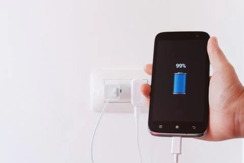 Female hand plugging in the plug of her smartphone in a socket Stock Photos