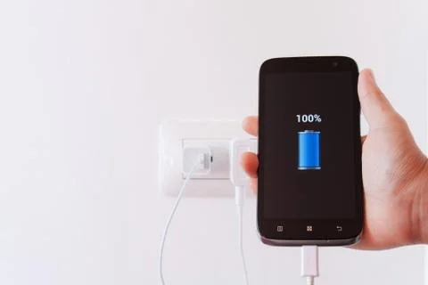 Female hand plugging in the plug of her smartphone in a socket Stock Photos