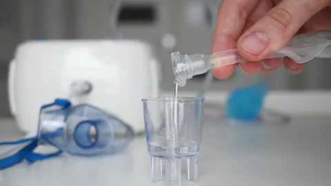 Female hand pours saline solution into inhaler measuring cup for inhalation Stock Footage 231395555