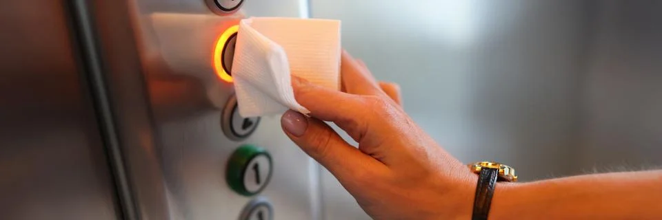 Female hand presses button in elevator through napkin. Foto stock