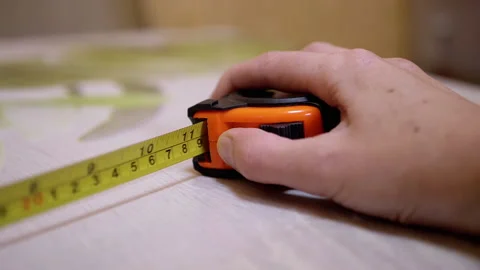 Female Hand Presses Button of an Orange Metallic Inch Tape with a Return Spring Video stock 163580786