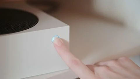 Female hand presses with button to turn off the Xbox Series S game console Stock Footage 149458847