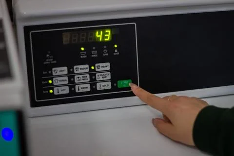 Female hand pressing start button on washing machine control panel Stock Photos