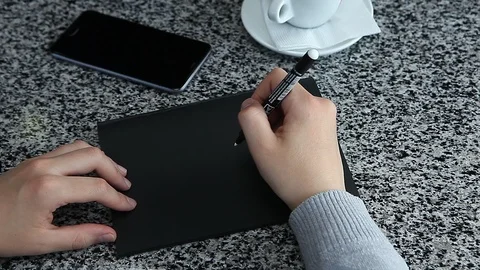 Female hand pretending to write on black paper laying table Stock Footage 89092039