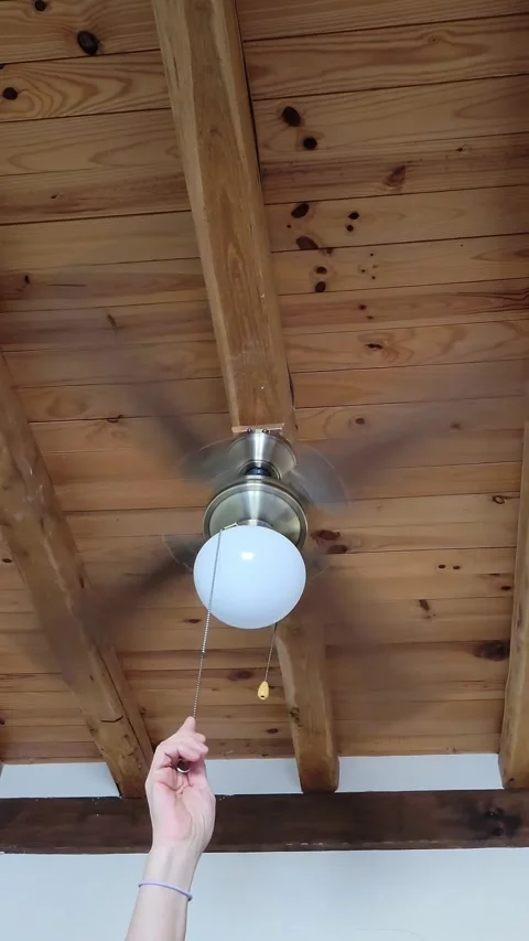 Female hand pulling a chain cord to switch on the light of a vintage ceiling fan Stock Footage 331850693