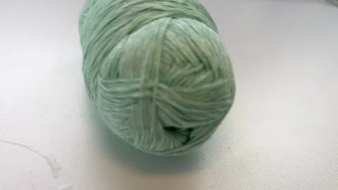 Female hand pulling thread of cotton linen yarn on white table. Crocheting and Stock Footage 266948866