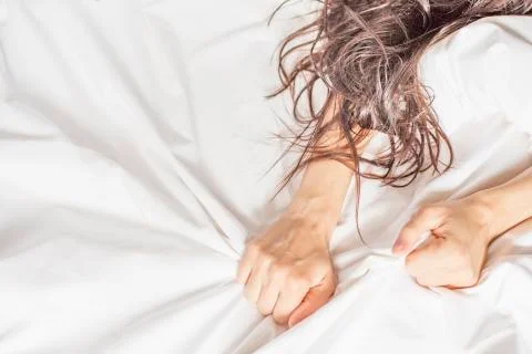 Female hand pulling white sheets in ecstasy, orgasm. Stock Photos