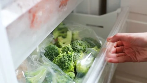 Female hand pulls frozen broccoli out of the freezer close-up Stock Footage