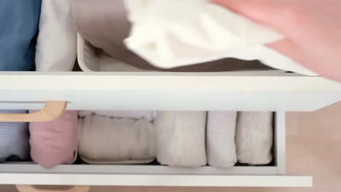 Female hand pulls out folded clothes from closet top view. 库存影片 237443043