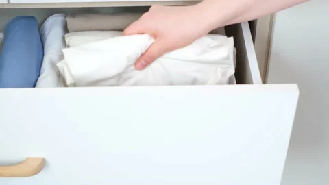 Female hand pulls out folded clothes from closet top view. 库存影片 237591814