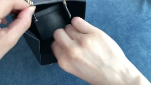 Female hand pulls out a gift box from a black package on a blue background Stock Footage 152971357