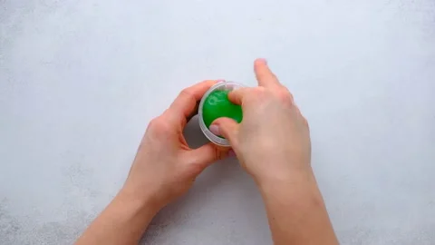 Female hand pulls out green slime from a plastic jar. Trendy liquid toy. Top Stock Footage 152216618