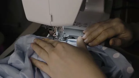 A female hand pushes material through a sewing machine. Sewing Process Stock Footage 146270083
