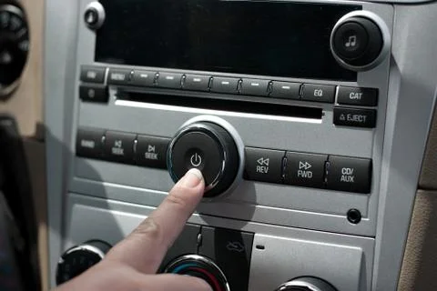 A female hand pushing the power button to turn on the car stereo system. Stock Photos