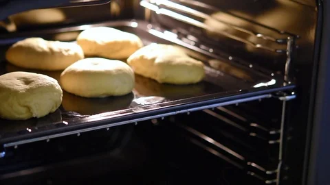 A female hand puts a baking tray with handmade bread inside a home oven. Stock-Footage 77138209