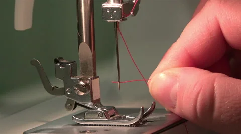 Female hand puts a red silk thread in the needle of the sewing machine Stock Footage 67845083