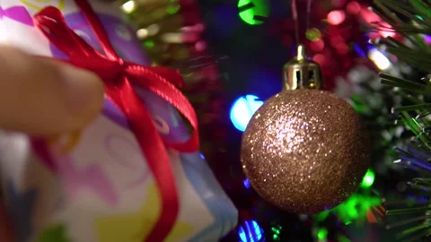 A female hand puts a small gift box with a red ribbon under the tree.New Year's Stock Footage 167624837
