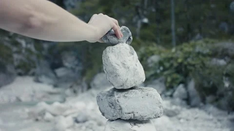 Female hand puts stone on stack or cairn zen meditation in autumn in Alps Stock Footage 139773455