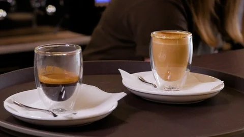 Female hand puts two cups of coffee on a white plates in cafe. Close up. Stock Footage 106816764