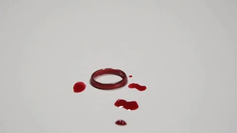 Female hand puts a wedding ring covered in blood on a white surface. Stock Footage 82900476