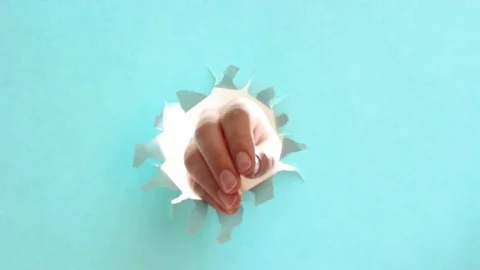 Female hand raises thumb up on torn blue paper background. Stock Footage 124521904