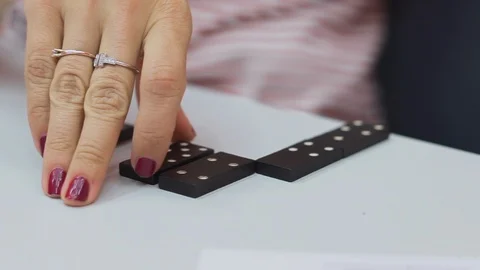 Female hand with red manicure grabs black domino tile Stock Footage