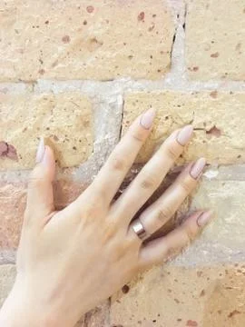 Female hand with a ring on a light brick wall Stock Photos