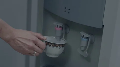 Female hand serving water of a water cooler in glass cup. Poured from water Stock Footage