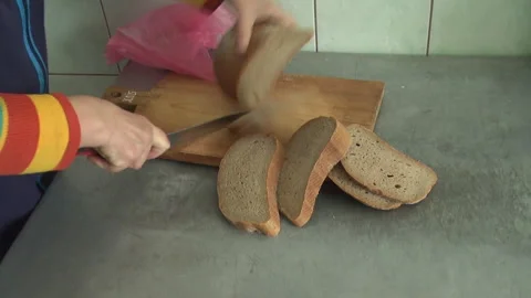 Female Hand with Sharp Knife Slicing Cut Sourdough Bread. Stockbeeldmateriaal 308826061