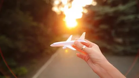 Female hand simulates a flight with plastic airplane in the evening. Stock Photos
