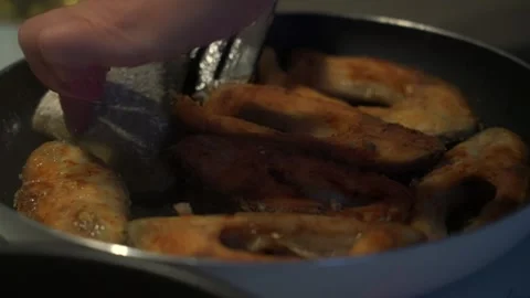 Female hand with spatula preparing fried fish on skillet Stock Footage 180637026