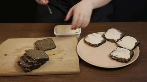 A female hand spreads rye bread with bran cream cheese with a knife 库存影片 129063280