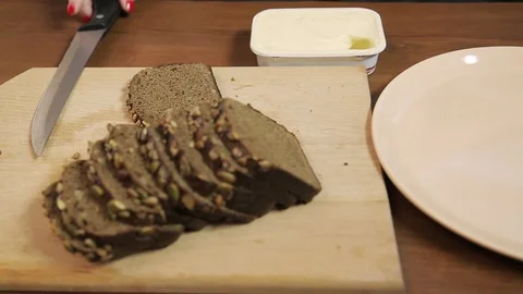 A female hand spreads rye bread with cream cheese using a knife. 库存影片 130032463