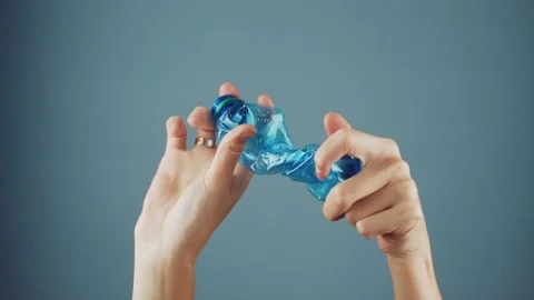 Female hand squeezes an empty plastic bottle Stock Footage 145348323