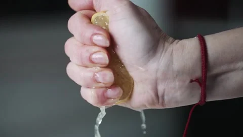 Female hand squeezing fresh lemon on blurred background. Slow motion view of a Stock Footage 231286357
