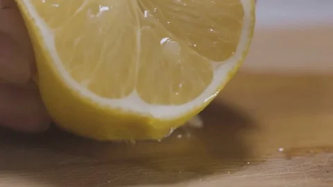 Female Hand Squeezing Fresh Lemon Juice on Wooden Board Видео 334563121