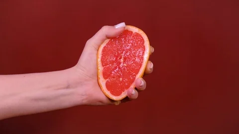 Female hand squeezing grapefruit isolated on red Stock Footage 123464769