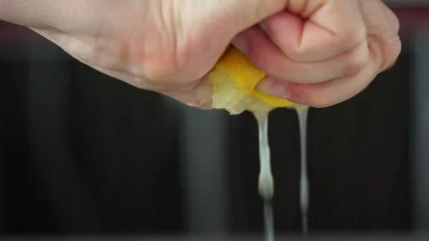 Female hand squeezing half of lemon on dark background. Close up Stock Footage 156646923