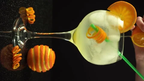 Female hand squeezing an orange into gin cocktail, 4k vertical video, close up Stock Footage 156409716