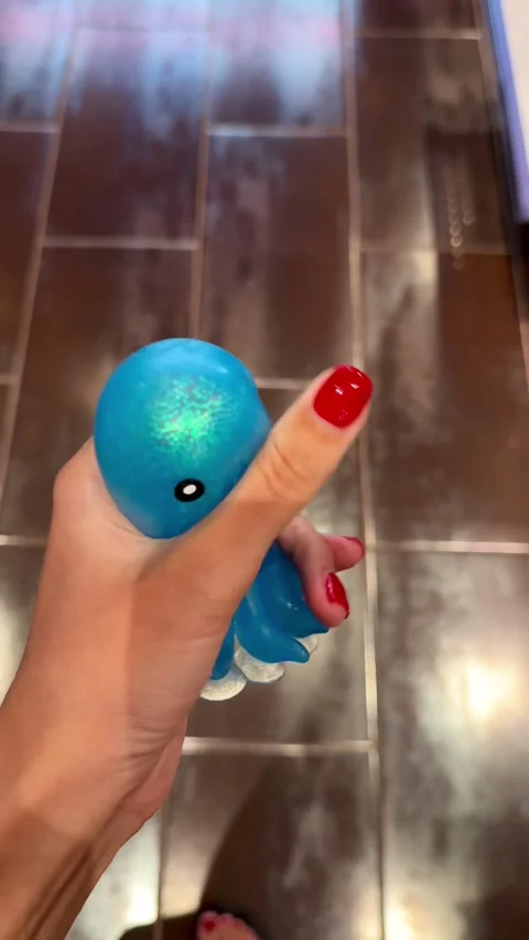 Female hand squeezing a shiny blue octopus squishy toy 库存影片 342336809
