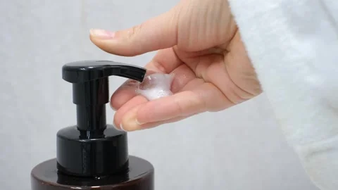 Female hand squeezing soap foam from black dispenser on gray background. Stock Footage 329539995