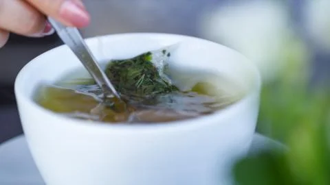 Female hand stirring a cup of herbal tea with a spoon Stock Photos