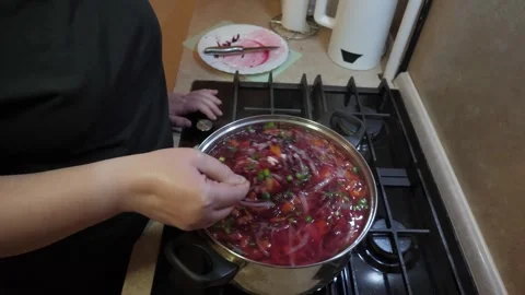 Female hand stirring large red soup pot on gas stove Vidéo 342362948