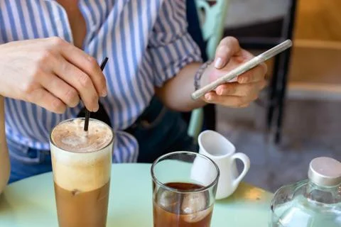 Female hand stirring a straw on a greek cold coffee, freddo cappuccino, outdoors Stock Photos