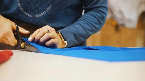 Female hand with tailor scissors or shears cutting out fabric at studio Stock Footage 97899759