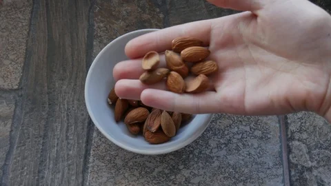 Female Hand Takes Nuts. Girl Takes a Handful of Almonds from a Plate Stock Footage